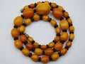 baltic amber, amber, antique, amber beads, egg Yolk, amber chain, Rosary beads, مسبحة, Masbaha, Muslim prayer beads حبيت الدورة ,العنبر الهندى, A multi-strand beaded necklace featuring polished oval amber-orange beads separated by small dark brown spacer beads, with two small metallic spacers, displayed on a light gray background.