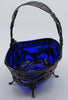 Angled view of the blue glass liner within a pierced silver basket decorated with floral garlands.