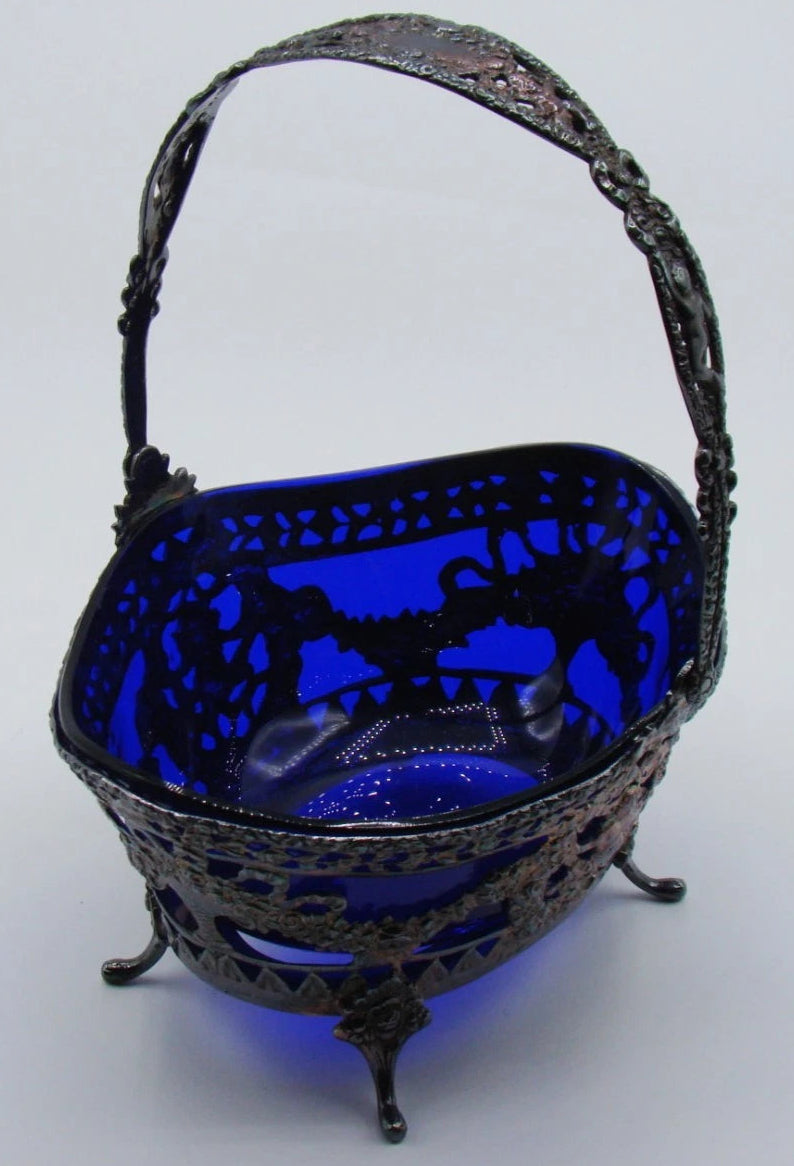 Angled view of the blue glass liner within a pierced silver basket decorated with floral garlands.