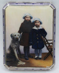 900 silver cigarette case with a colourful scene of two children and a dog, framed by a blue-and-white border.