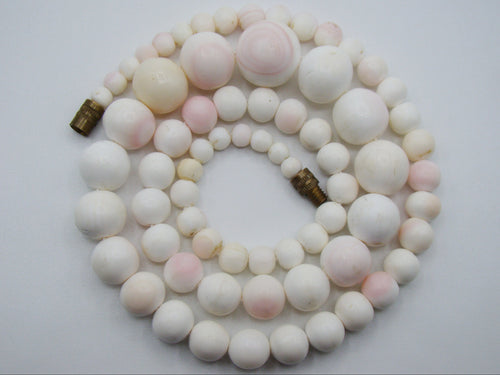 1930s White Angel Skin coral necklace arranged in a coil, showing graduated white and blush-pink beads
