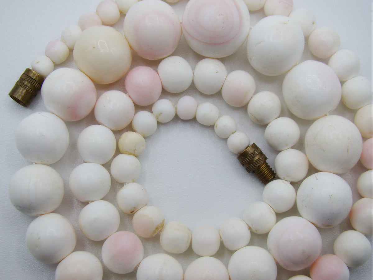 Detail of graduated white and pink coral beads showing surface texture and colour variation