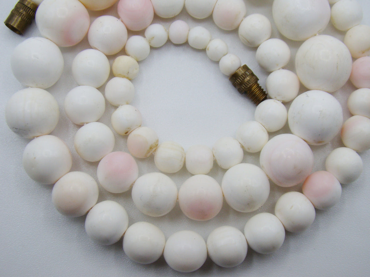 Close view of the larger rounded coral beads and smaller beads beside the clasp