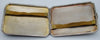 Open silver cigarette case showing the hinged interior and two discoloured retaining straps.