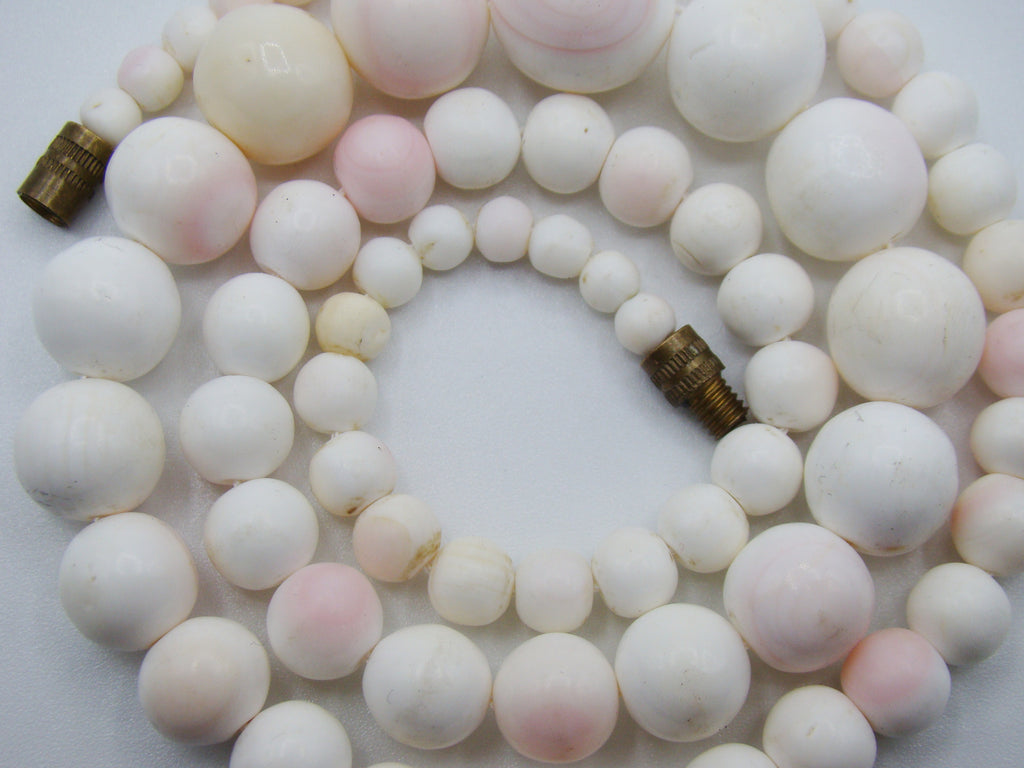Detail of the coral necklace with blush-pink tones and visible bead surface irregularities