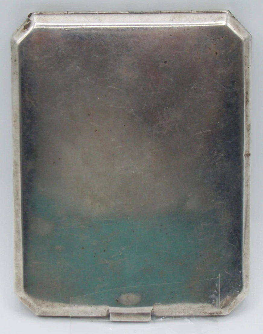 Plain silver reverse of the cigarette case showing surface scratches, patina and clipped corners.