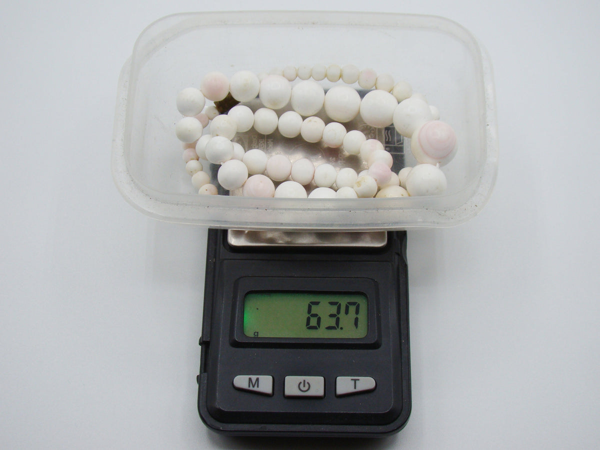 Coral necklace in a container on a digital scale displaying 63.7 grams