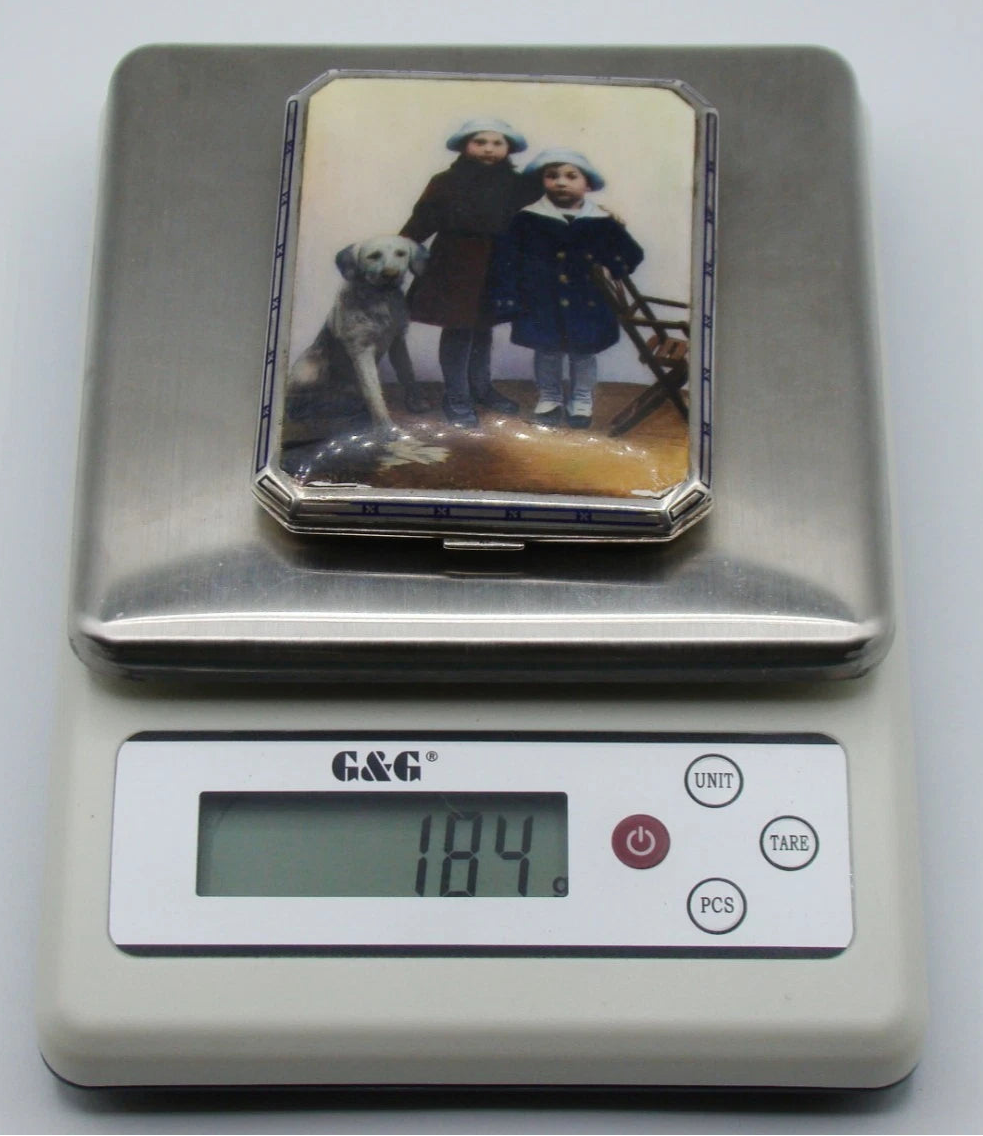 Decorated silver cigarette case on a digital scale displaying a total weight of 184 grams.