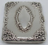 Portrait-oriented view of the ornate silver case with a row of stamped marks beside the central cartouche.