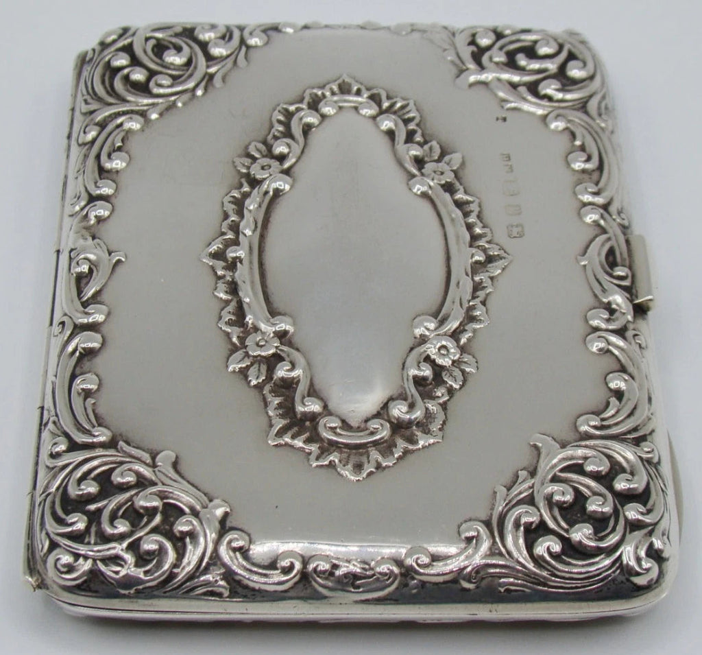 Portrait-oriented view of the ornate silver case with a row of stamped marks beside the central cartouche.