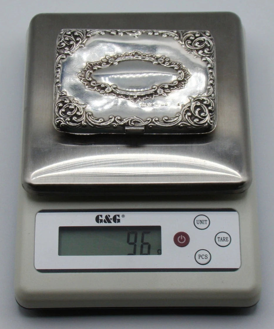 Silver cigarette case on a digital scale displaying a total weight of 96 grams.