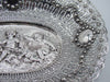 Right-hand detail of the silver tray showing a cherub and floral-framed oval cartouche