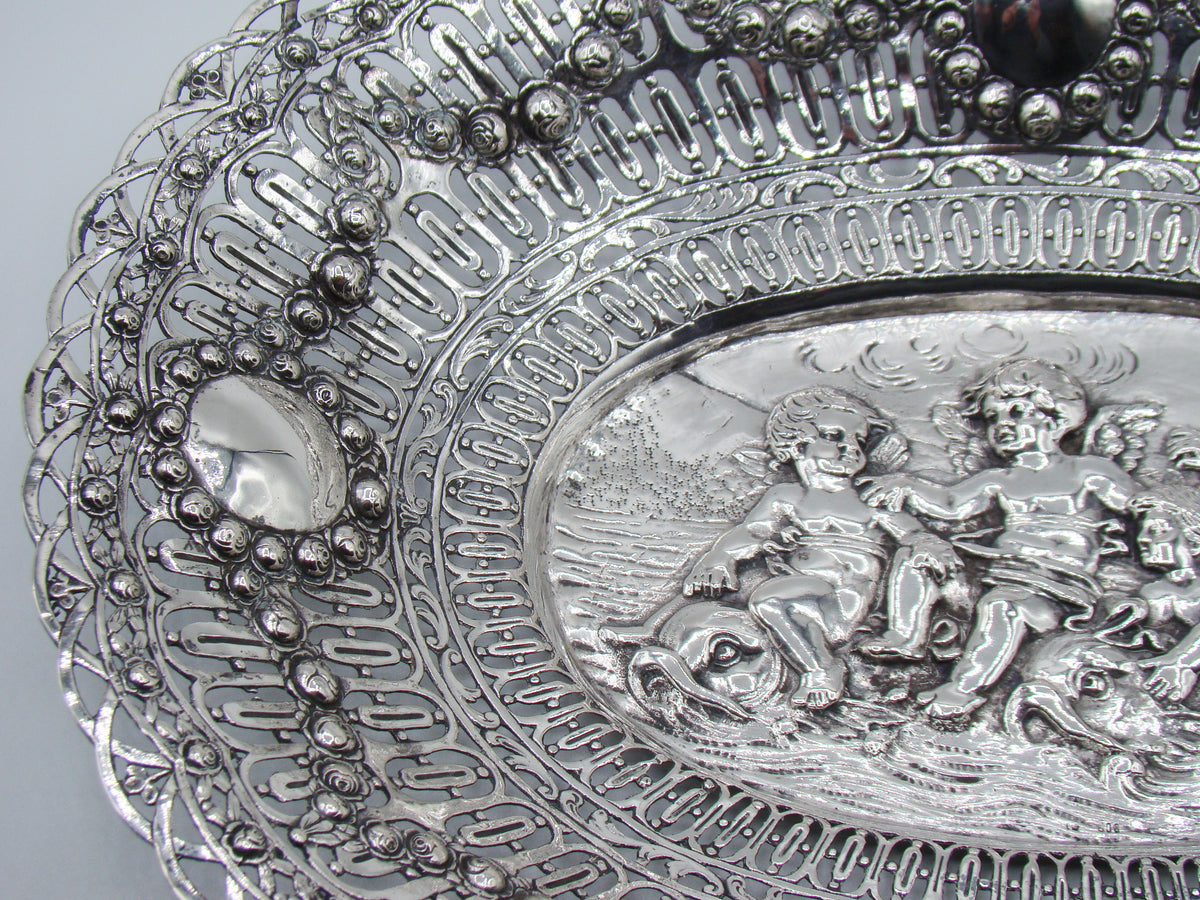 Left-hand detail of the silver tray with scrolling openwork and raised cherub decoration