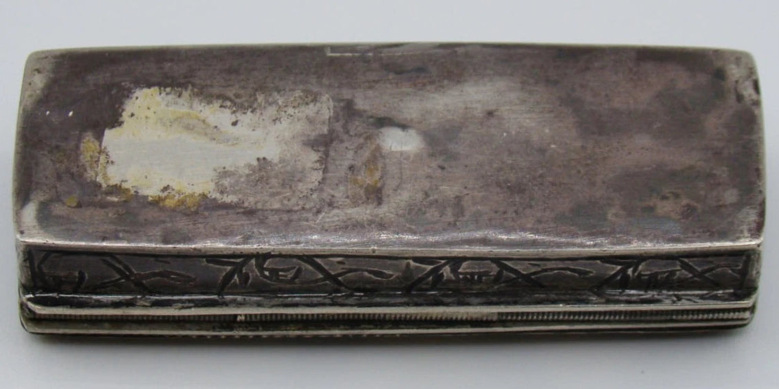Underside of the silver box showing tarnish, scratches and a pale surface patch