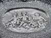 Close-up of three winged cherubs with stylised aquatic creatures in the tray's central relief