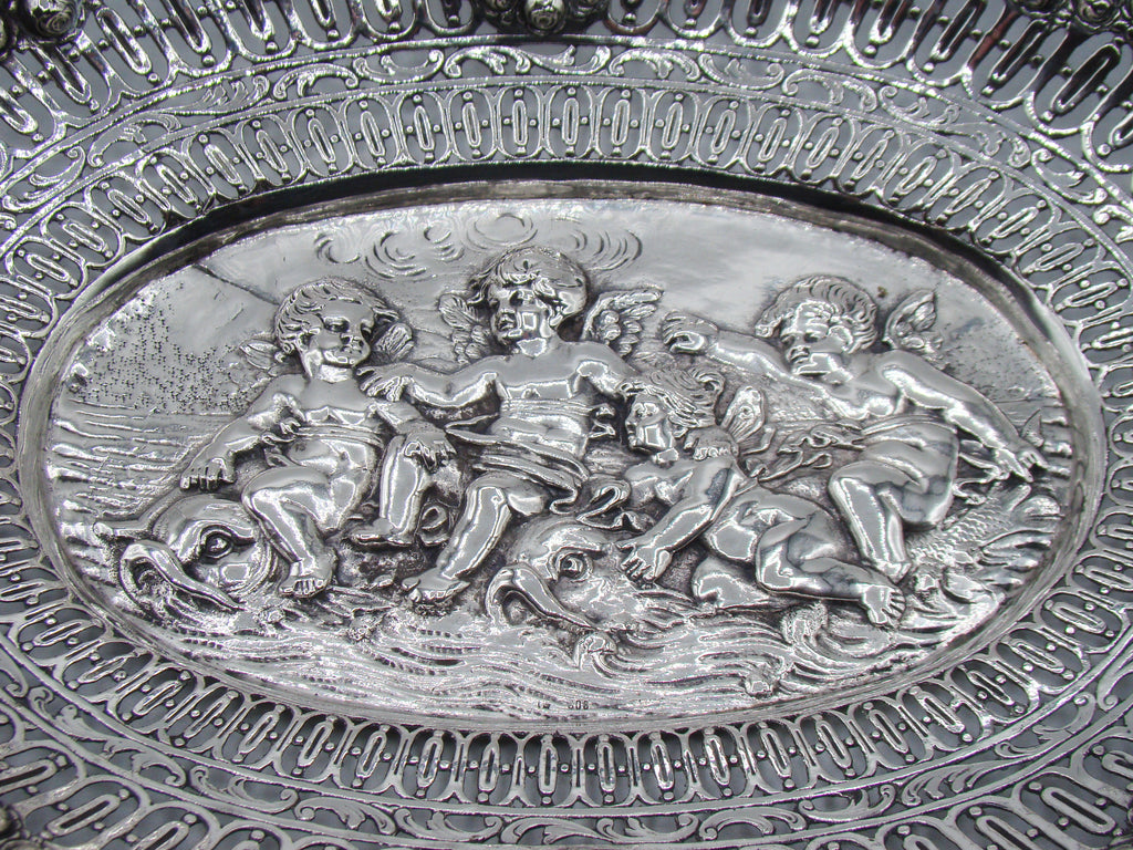 Close-up of three winged cherubs with stylised aquatic creatures in the tray's central relief