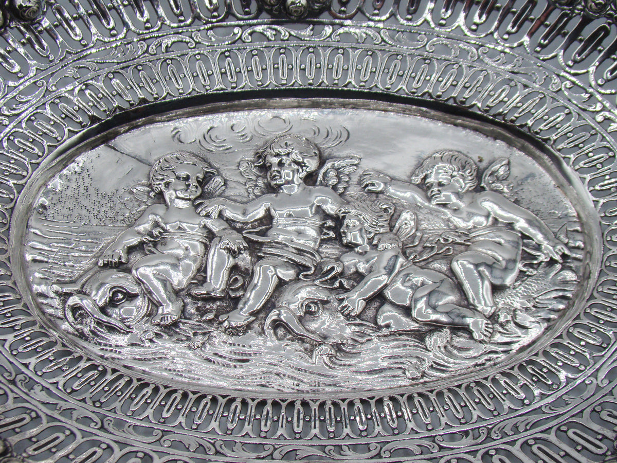 Close-up of three winged cherubs with stylised aquatic creatures in the tray's central relief