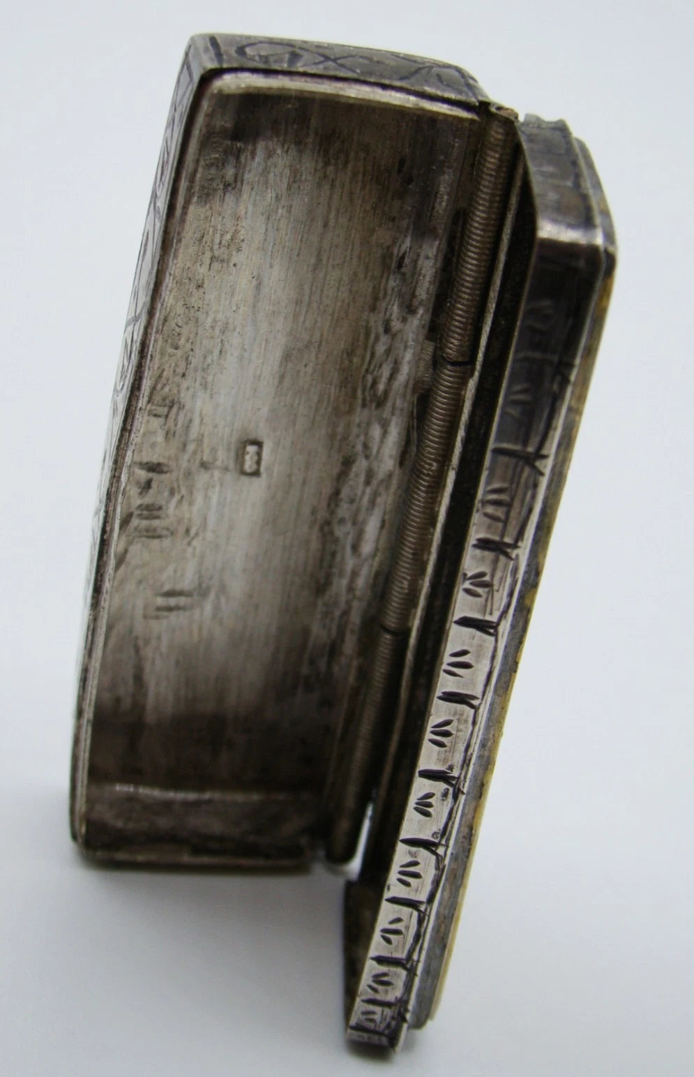 Angled interior view of the open miniature silver box with a small stamped mark