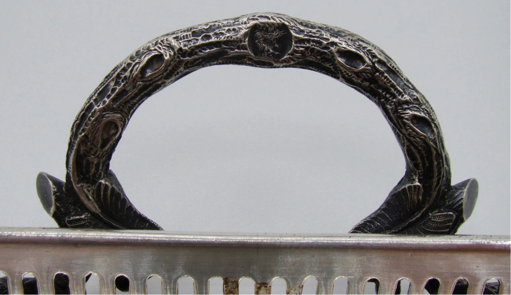 Detail of an ornate textured loop handle and its leaf-shaped attachments
