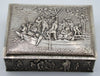 Front view of the silver box with figures aboard a boat on the lid and detailed relief decoration below.