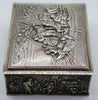 Angled view of the silver box showing the scrolling lid border and figurative side panel.