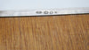Close-up of four stamped marks on the silver underside rim beside the wooden base panel.