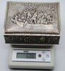 Decorated silver box on a digital scale reading 606 grams, including its wooden components.