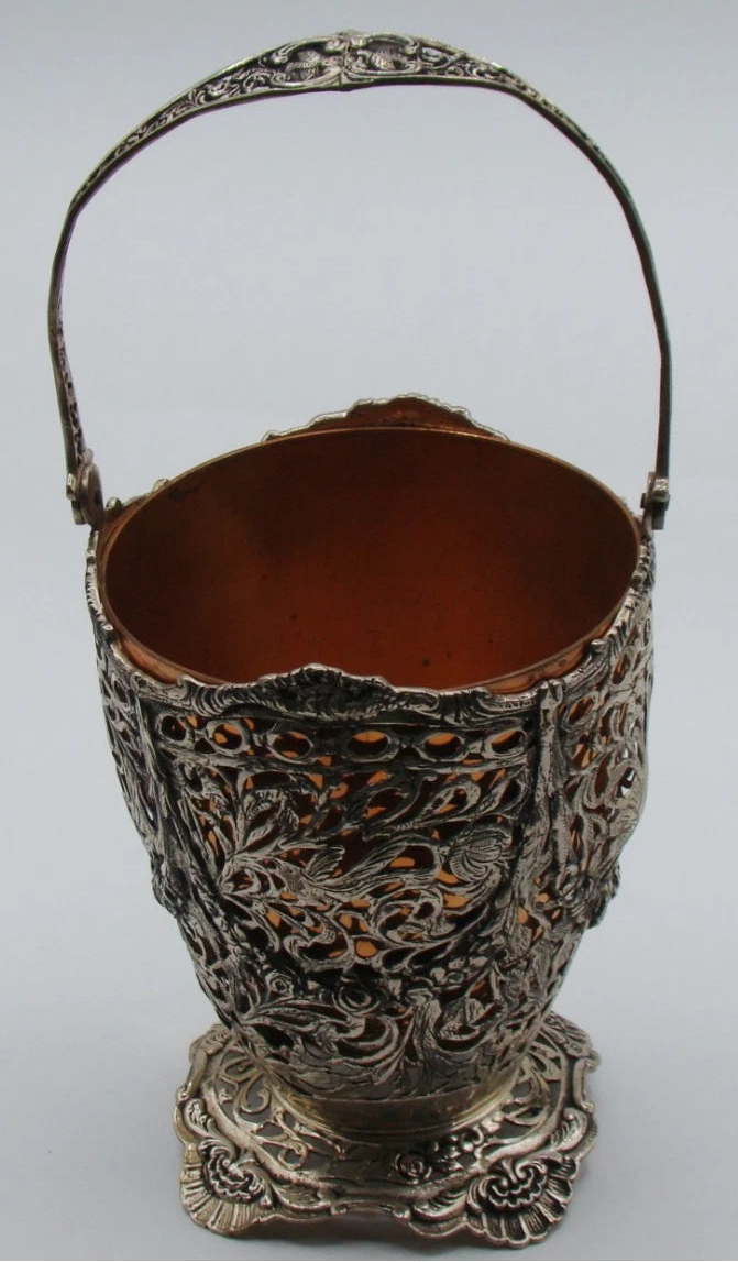 Front view of the silver basket with scalloped rim, scrolling foliage, and copper-coloured insert.