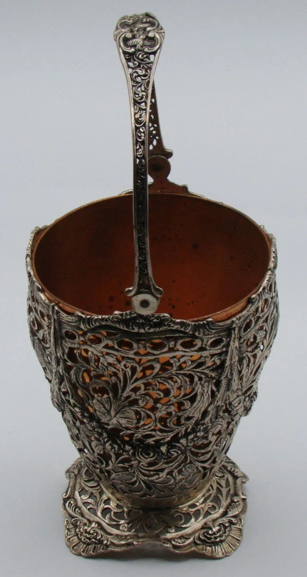 Side view of the silver basket showing the handle attachment and ornate pedestal foot.