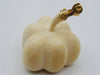 A small sculptural pumpkin-shaped object in a warm ivory or cream tone with a metallic gold stem detail, photographed on a plain light background.