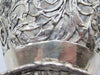 Close-up of the 800 stamp on the silver basket beside its pierced leaf decoration.