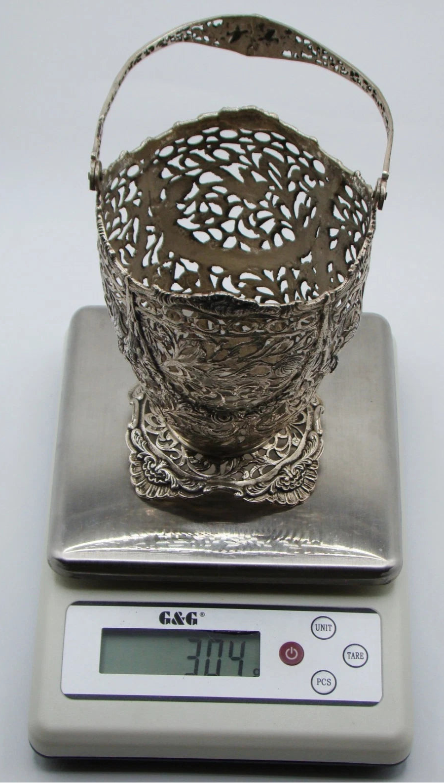 Silver basket without its removable insert on a digital scale reading 304 grams.