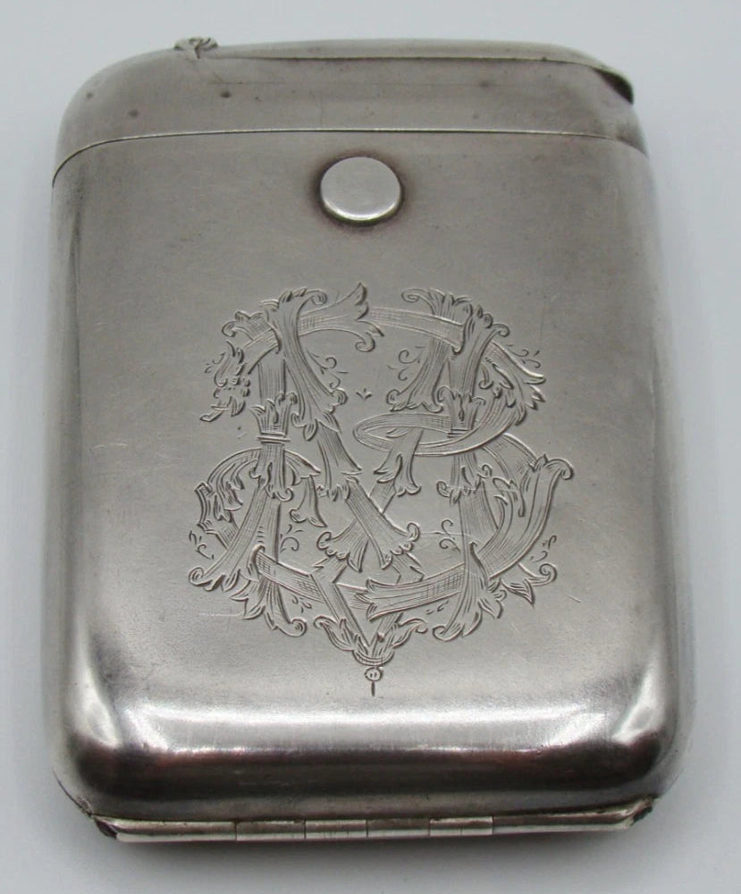Front of 900 silver cigarette case with ornate engraved monogram, rounded corners, and round button.
