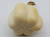 A cream-colored carved bone or ivory figurine shaped like a flower bud with a small gold-colored loop at the top, set against a plain light gray background.