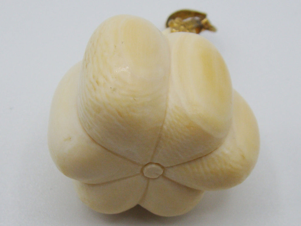 A cream-colored carved bone or ivory figurine shaped like a flower bud with a small gold-colored loop at the top, set against a plain light gray background.