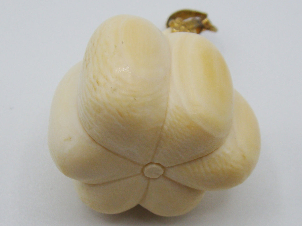 A cream-colored carved bone or ivory figurine shaped like a flower bud with a small gold-colored loop at the top, set against a plain light gray background.