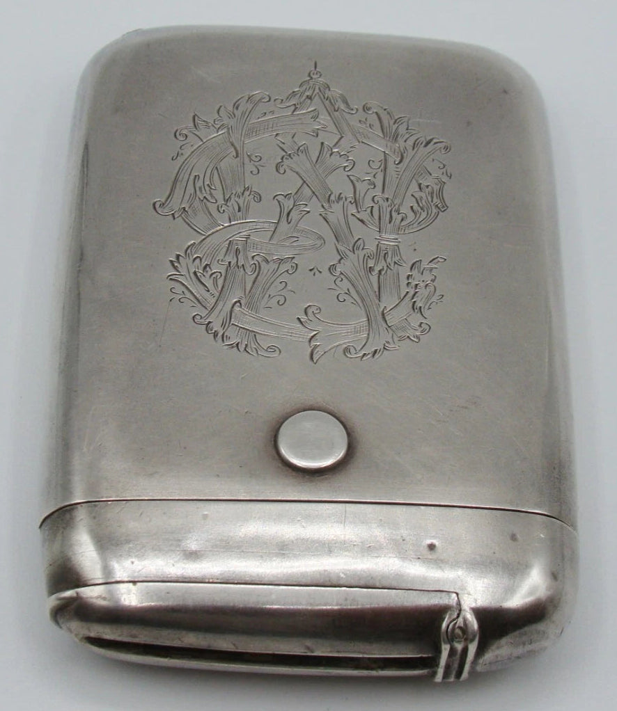 Upright view of the monogrammed silver case with its narrow compartment closed.