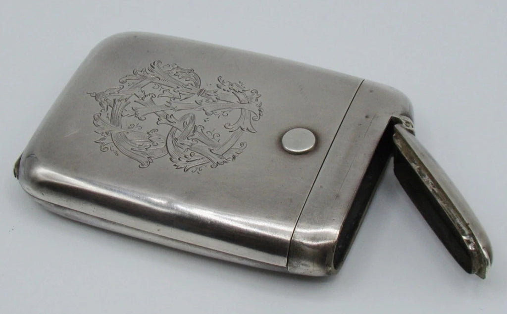 Silver monogrammed cigarette case with the narrow side compartment open.