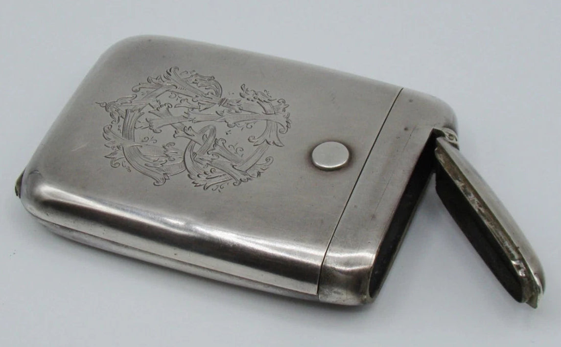 Silver monogrammed cigarette case with the narrow side compartment open.