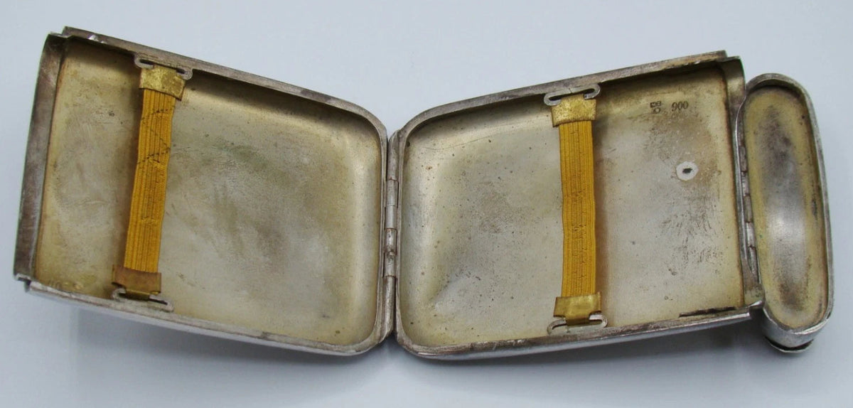 Open silver cigarette case showing two golden-yellow retaining bands and interior marks.
