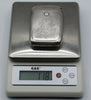 Monogrammed silver cigarette case on a digital scale displaying 118 grams.