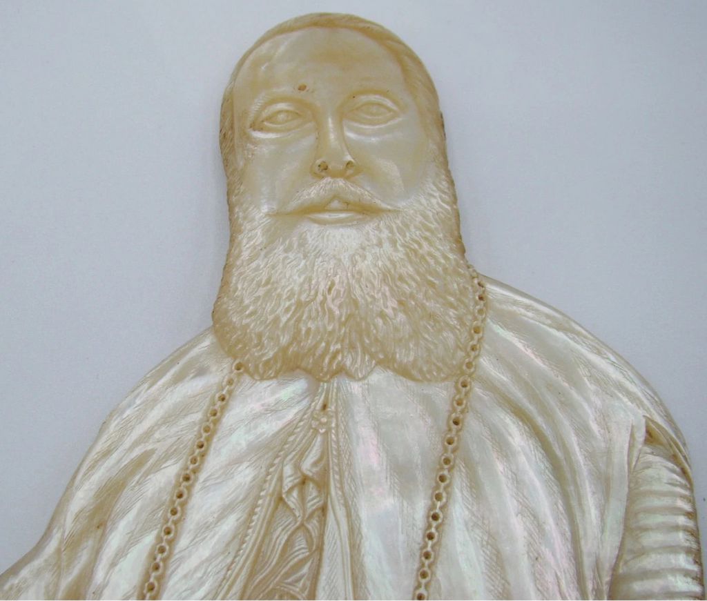 Inverted view of mother-of-pearl portrait showing robe folds, cross and carved chain