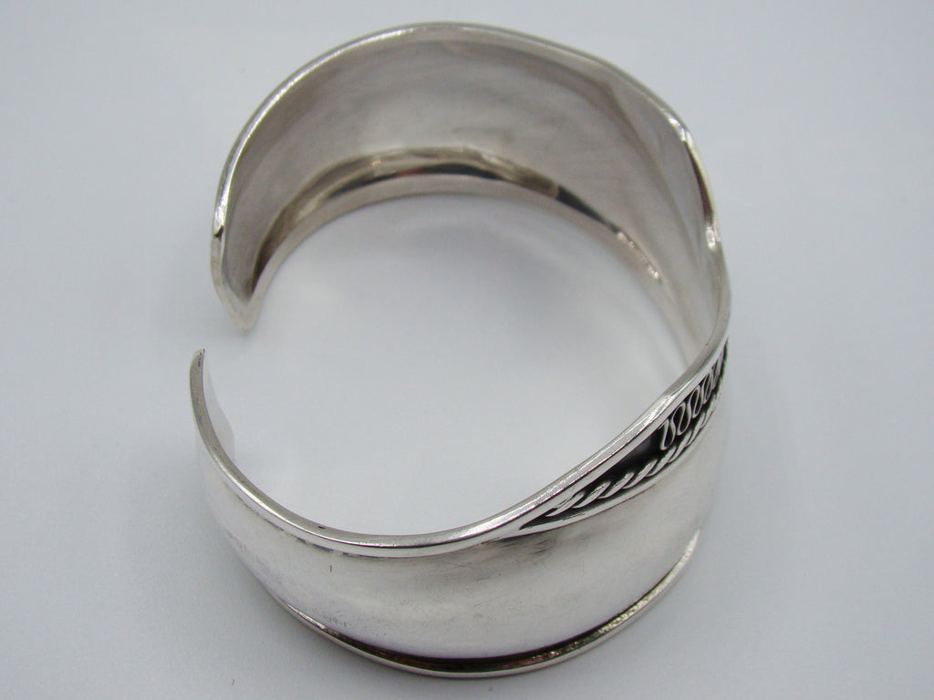 Rear view of the silver cuff bracelet showing the open gap, smooth interior, and bordered ends.