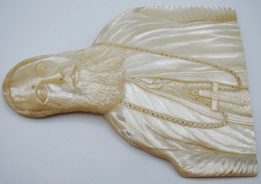 Sideways view of the mother-of-pearl bishop portrait showing the relief carving