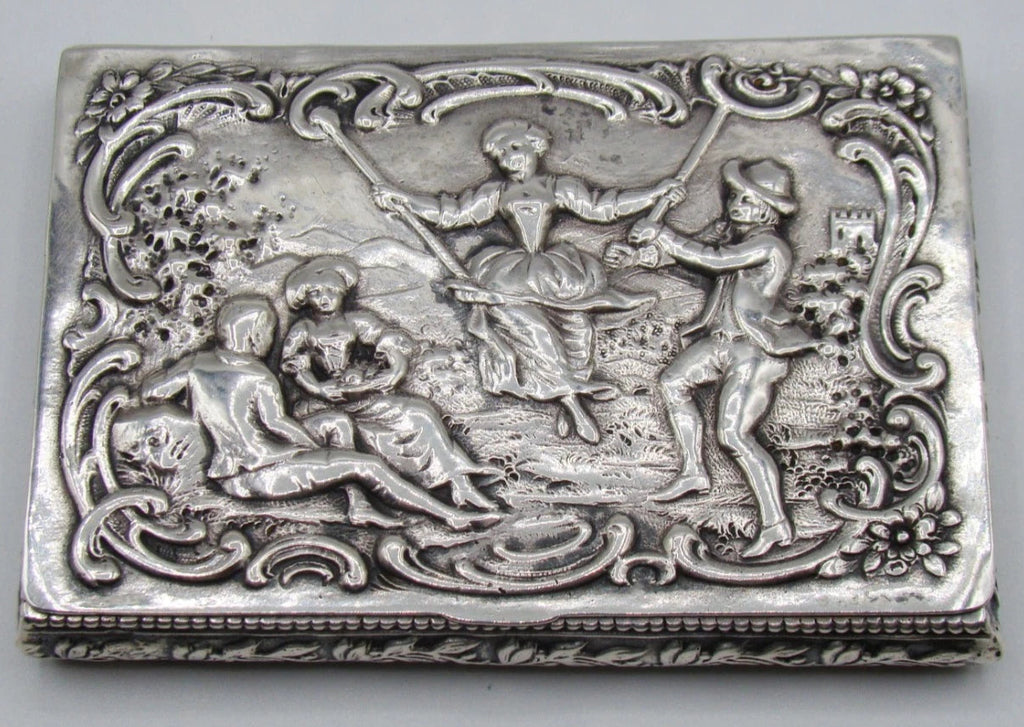 800 silver rectangular box with pastoral relief scene, a figure on a swing, and floral scrollwork border.