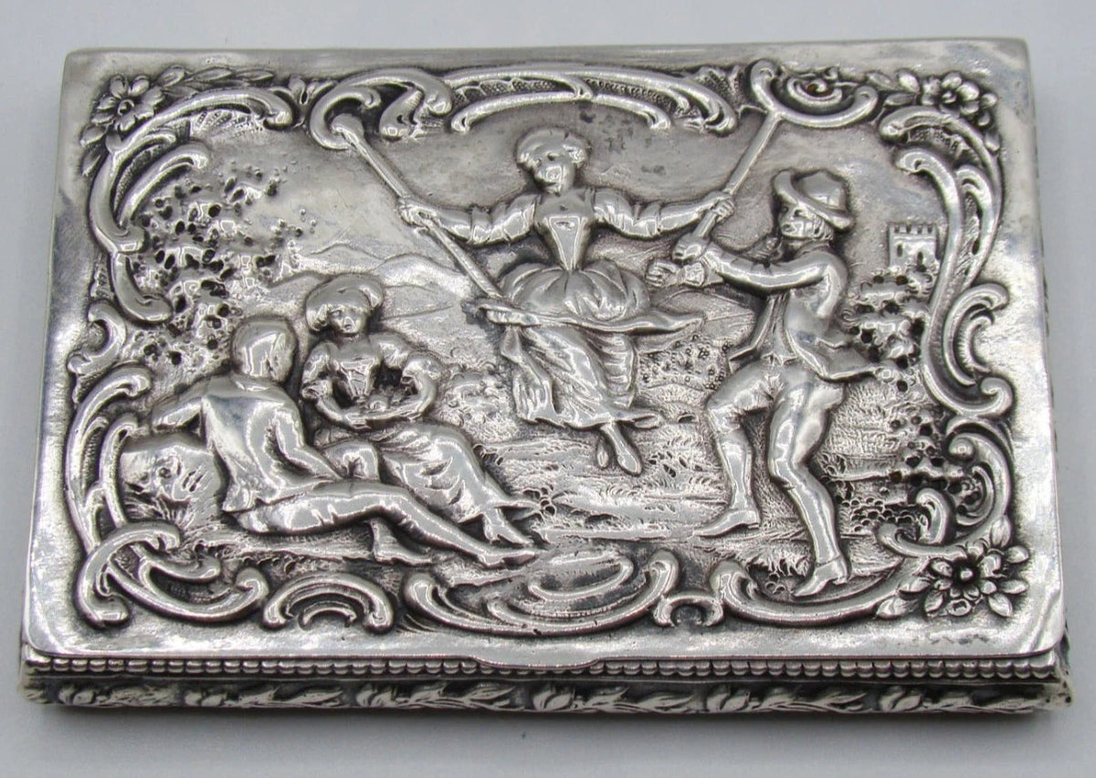 800 silver rectangular box with pastoral relief scene, a figure on a swing, and floral scrollwork border.