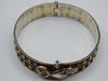 Silver hinged bangle with sculpted hand-motif fastening, round bird detail, and rope-like borders.