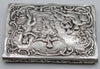Angled view of the silver box lid with pastoral figures and leafy ornament on the shallow sides.