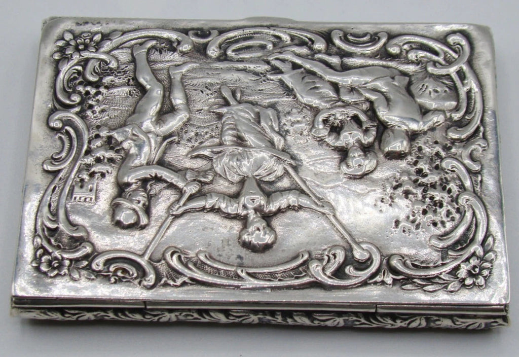 Angled view of the silver box lid with pastoral figures and leafy ornament on the shallow sides.