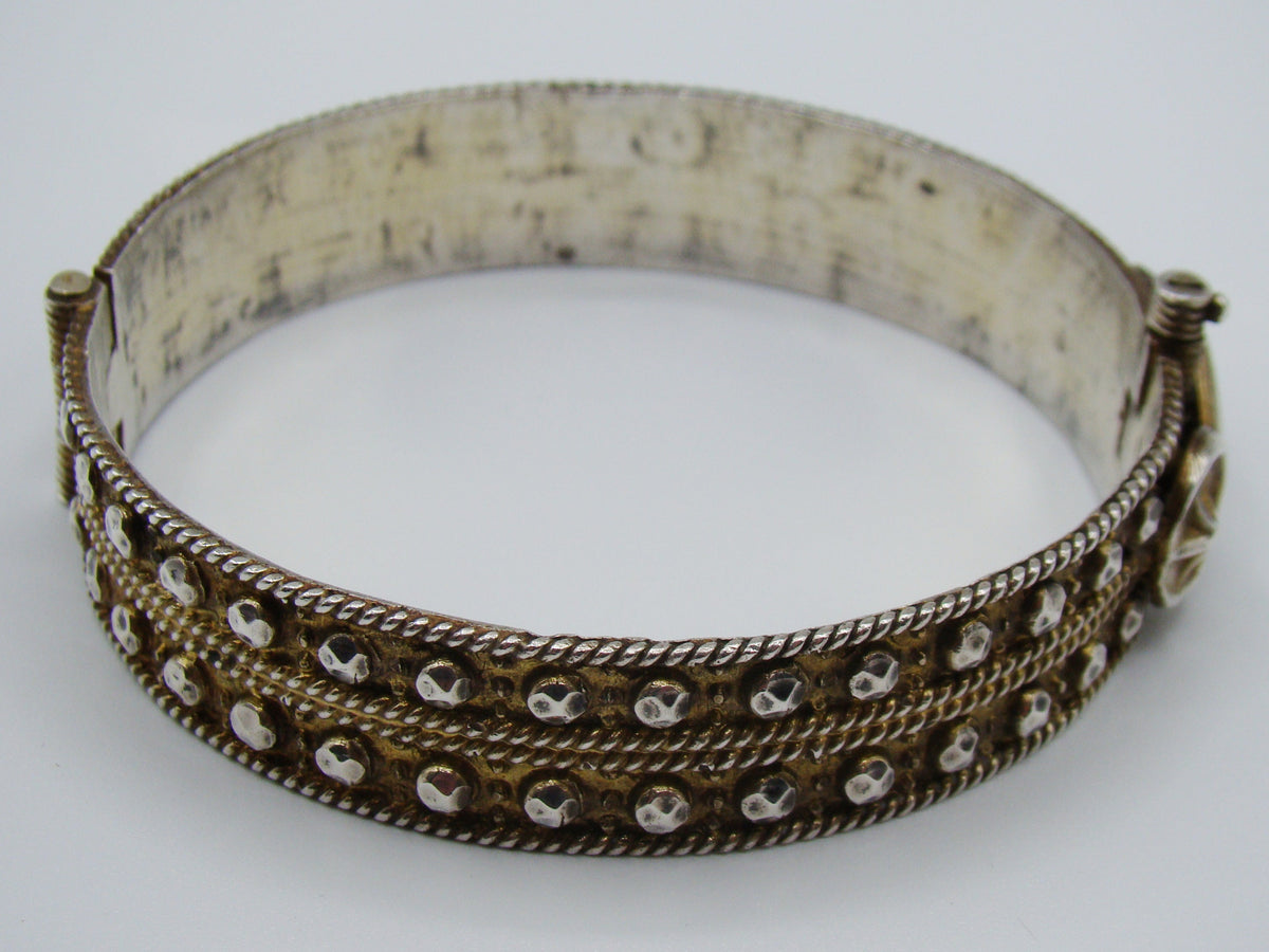 Rear view of the decorated silver bangle showing its hinge and twisted-wire horizontal bands.